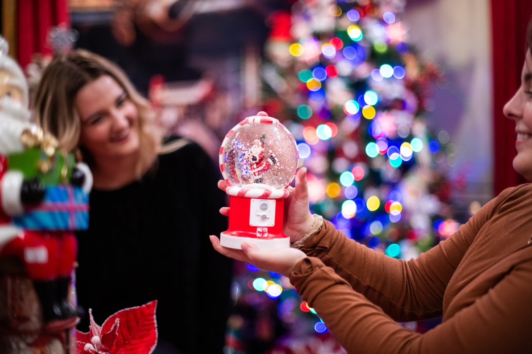 2 girls surrounded by Christmas lights holding up a snow globe