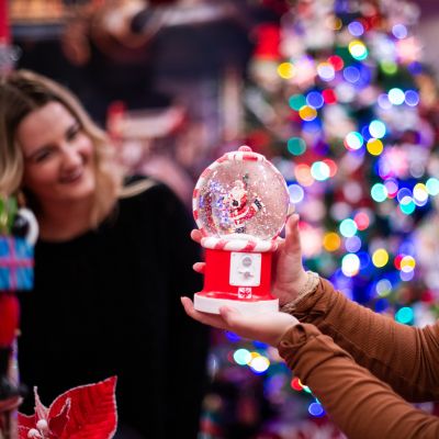 two women holding up a snow globe surrounded by christmas decor